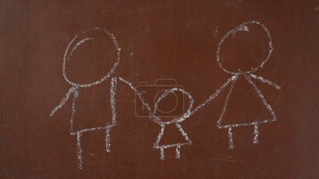 Photo for Textured brown chalkboard background. A child drawing of a family is sketched on the board with a piece of white chalk. Close up. Educational and creative content, school concept. - Royalty Free Image