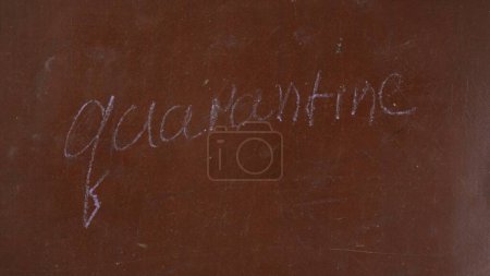 Photo for Textured brown chalkboard background. Quarantine is written on the board with a piece of purple chalk. Close up shot. Educational and creative content, healthcare concept. - Royalty Free Image