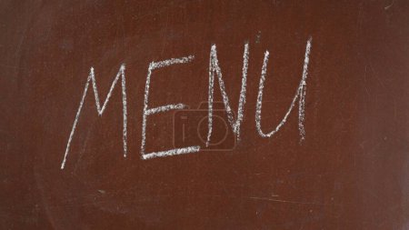 Photo for Textured brown chalkboard background. Menu is written on the board with a piece of white chalk. Close up shot. Educational and creative content, food and drink, catering concept. - Royalty Free Image