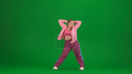 Photo for Attractive woman dancing jazz-funk on green screen chroma key background in a studio. Modern dynamic and energetic dance choreography. Full length. Creative content, promotional clip or advertisement. - Royalty Free Image