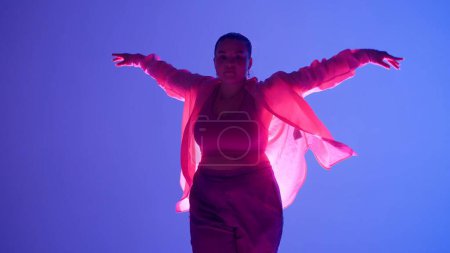 Foto de Atractiva mujer bailando jazz-funk en luz de neón rosa y azul en un estudio. Coreografía de danza moderna dinámica y enérgica. Medio lleno. Contenido creativo, clip promocional o publicidad. - Imagen libre de derechos