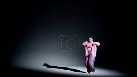 Foto de Mujer atractiva bailando jazz-funk en un estudio. Fondo de degradado suave de negro a blanco, foco blanco y sombra que cae distinta. Coreografía moderna. Longitud total. Clip promocional o - Imagen libre de derechos