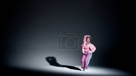 Foto de Mujer atractiva bailando jazz-funk en un estudio. Fondo de degradado suave de negro a blanco, foco blanco y sombra que cae distinta. Coreografía moderna. Longitud total. Clip promocional o - Imagen libre de derechos