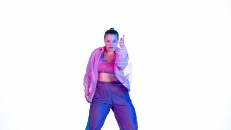 Foto de Atractiva mujer bailando jazz-funk sobre fondo blanco aislado en un estudio. Proyector azul y rosa, coreografía de danza enérgica. Medio lleno. Contenido creativo, clip promocional o publicidad. - Imagen libre de derechos
