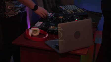 Photo for Close up shot capturing hands of a man playing and mixing music on a DJ console. Neon colorful lights. Nightlife, advertisement or creative content for younger viewers. - Royalty Free Image