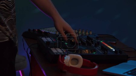 Photo for Close up shot capturing hands of a man playing and mixing music on a DJ console. Neon colorful lights. Nightlife, advertisement or creative content for younger viewers. - Royalty Free Image
