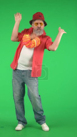 Téléchargez les photos : Concept créatif moderne pour seniors. Portrait de hipster senior sur fond Chroma écran vert clé, homme dansant à la caméra. Espace publicitaire, maquette d'espace de travail. Photo verticale. - en image libre de droit