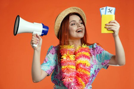 Photo for Travelling advertisement concept. Studio shot of female model. Close up of excited woman holding megaphone and flight tickets with passport, smiling looking at them, isolated on orange background. - Royalty Free Image