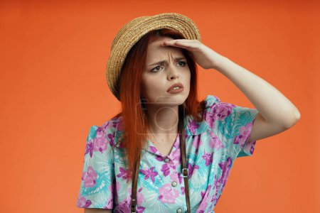 Photo for Travelling advertisement concept. Studio shot of female model. Close up of woman in hat standing holding hand over forehead looking for something with upset tired face, isolated on orange background. - Royalty Free Image