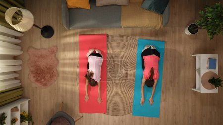 Téléchargez les photos : Dans la photo ci-dessus, une femme et un enfant se tiennent dans une pièce sur un tapis de fitness. Démontrant une posture de yoga, ils tirent leurs bras vers l'avant, s'étirant. La femme enseigne à la fille comment le faire correctement. - en image libre de droit