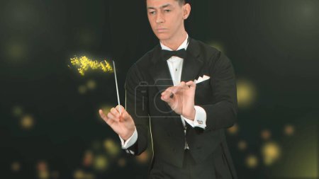 Photo for Close up on a black background stands a young man in a tuxedo, holding a wand in his hands. Depicts a conductor with a baton from which notes are issued. Creates a magical, musical atmosphere. - Royalty Free Image