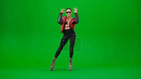 Téléchargez les photos : Style de danse moderne concept publicitaire créatif. Jolie danseuse debout posant en talons hauts sur fond d'écran vert chroma clé dans un studio. Espace publicitaire, maquette de l'espace de travail. - en image libre de droit