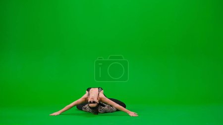Téléchargez les photos : Style de danse moderne concept publicitaire créatif. Danseuse flexible allongée sur le sol en talons hauts sur fond de studio à écran vert chromé. Espace publicitaire, maquette de l'espace de travail. - en image libre de droit