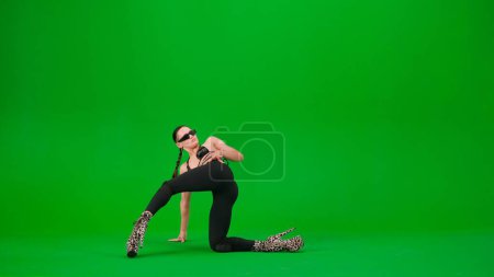 Téléchargez les photos : Style de danse moderne concept publicitaire créatif. Femme danseuse posant sur ses genoux sur le sol en talons hauts sur fond de studio écran vert chroma clé. Espace publicitaire, maquette de l'espace de travail. - en image libre de droit