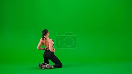 Photo for Modern dance style creative advertisement concept. Woman dancer in high heels posing on the floor with her back on chroma key green screen studio background. Advertising area, workspace mockup. - Royalty Free Image