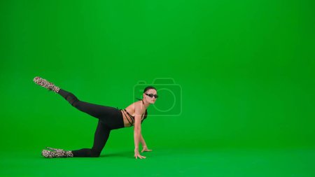 Téléchargez les photos : Style de danse moderne concept publicitaire créatif. Femme danseuse debout sur le sol avec la jambe en haut talons sur fond de studio écran vert chroma clé. Espace publicitaire, maquette de l'espace de travail. - en image libre de droit