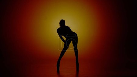 Photo for Modern dance style creative advertisement concept. Portrait of female dancer. Woman dancer silhouette in high heels standing in the studio in yellow spotlight. Isolated on colorful background. - Royalty Free Image