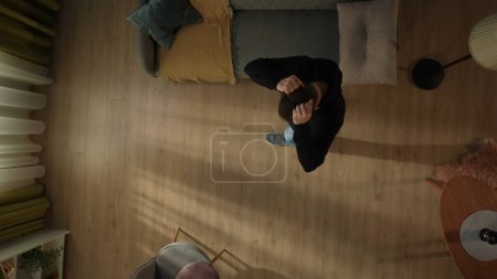 Photo for Top view of a helpless man in the living room. Man holding his head in despair. Depression, stress - Royalty Free Image