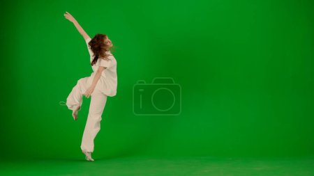 Foto de Moderna coreografía creativa y concepto de danza. Retrato de bailarina. Muchacha joven atractiva en el baile del traje blanco que muestra la danza contemporánea moderna en el fondo de pantalla verde de la llave de croma. - Imagen libre de derechos