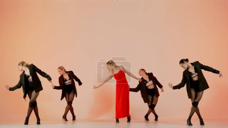 Photo for Framed against a pink background. Collective of young women in revealing clothing. Demonstrating a dance number, movement in the direction of high heels. They are beautiful, slender. Medium shot. - Royalty Free Image