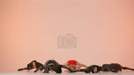Photo for Framed against a pink background. Collective of young women in revealing clothing. Demonstrate a dance number, movement in the direction of high heels, stretching. They are beautiful, slender, plastic - Royalty Free Image
