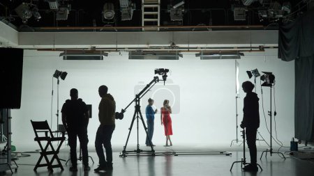 Foto de Pabellón de filmación profesional con un ciclorama blanco. El proceso de preparación para el rodaje de un vídeo musical. Director, camarógrafo y equipo en Backstage - Imagen libre de derechos