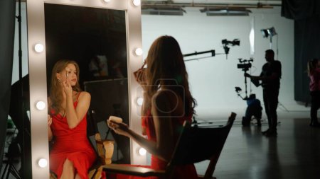 Téléchargez les photos : L'actrice se prépare à filmer un film. Elle s'assoit devant un miroir sur le plateau et se maquille. Concept des coulisses. - en image libre de droit