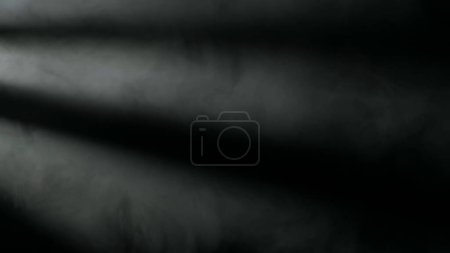Téléchargez les photos : Nuage de fumée grise sous les projecteurs sur un fond noir. Composition fantôme. Texture et art abstrait - en image libre de droit