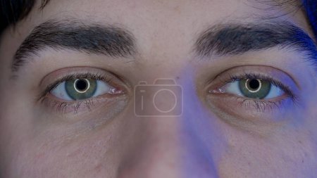 Photo for Eyes of a young man macro shot. Blue light from a smartphone, computer screen is reflected in the mans eyes. The concept of gadget abuse - Royalty Free Image