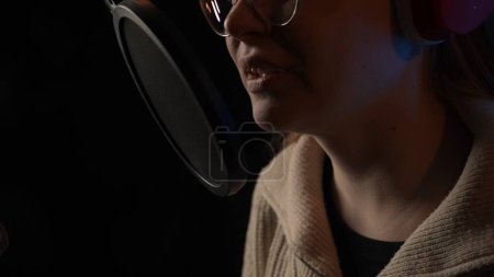 Photo for Beautiful young female dj speaks into microphone, records podcast or night news show for radio. Close up of podcast presenter or DJ talking on the microphone - Royalty Free Image
