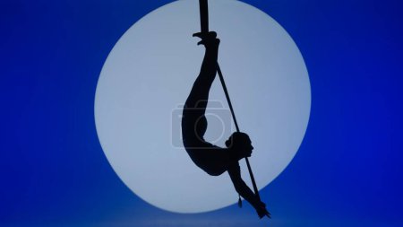 Foto de Chica de gimnasia rítmica realiza la escoria en un brazo en el aire en una luna estructura giratoria de metal - Imagen libre de derechos