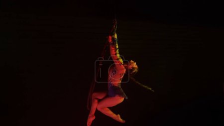 Foto de Chica de gimnasia rítmica realiza la escoria en un brazo en el aire en una luna estructura giratoria de metal - Imagen libre de derechos