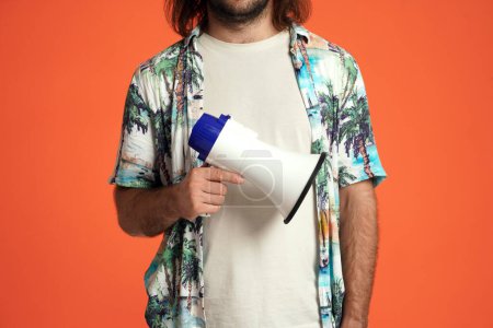 Photo for Megaphone in a mans hand close up. Male traveler with a megaphone in the studio on an orange background - Royalty Free Image