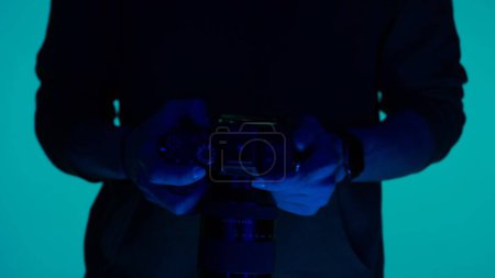 Photo for Professional male photographer working in studio. It uses colored neon lighting - Royalty Free Image