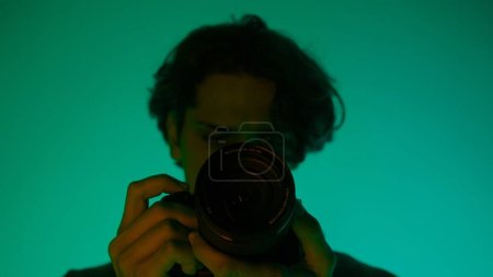 Foto de Fotógrafo masculino profesional trabajando en el estudio. Utiliza iluminación de neón de color - Imagen libre de derechos