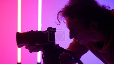 Foto de Fotógrafo masculino profesional trabajando en el estudio. Utiliza iluminación de neón de color - Imagen libre de derechos