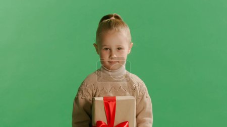 Téléchargez les photos : Portrait mignon petite fille enfant tenant boîte cadeau posant isolé sur fond jaune mur en studio. Concept de Noël. - en image libre de droit