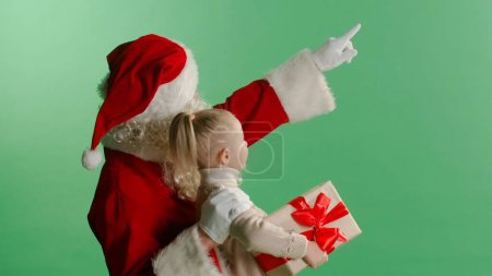 Téléchargez les photos : Joyeux Noël et joyeuses vacances Petite fille mignonne et Père Noël regardant étoile de Noël. Concept légende de Noël. - en image libre de droit