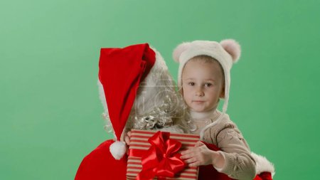 Foto de Santa Claus sostiene a una hermosa niña en sus brazos sobre un fondo verde - Imagen libre de derechos