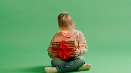 Téléchargez les photos : Portrait mignon petite fille enfant tenant boîte cadeau posant isolé sur fond jaune mur en studio. Concept de Noël. - en image libre de droit