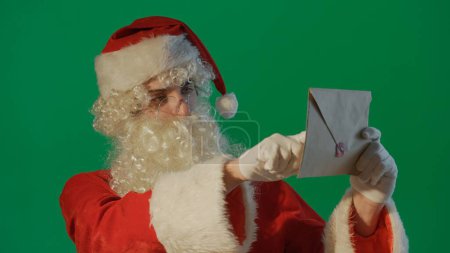 Foto de Retrato de Santa Claus leyendo una carta sobre un fondo verde - Imagen libre de derechos