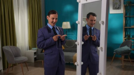Foto de Un hombre con un traje estricto está de pie en la sala de estar frente a un espejo. Personalidad dividida - Imagen libre de derechos