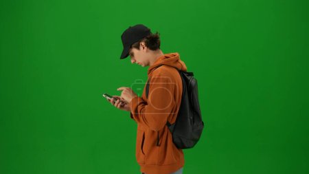 Photo for Airport creative advertisement concept. Portrait of person tourist isolated on chroma key green screen background. Close up shot young man holding smartphone and looking for departure information. - Royalty Free Image