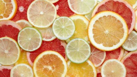 Photo for Yellow sliced citrus fruit places on a white table. Background texture of fresh colorful fruit - Royalty Free Image