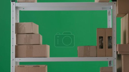 Téléchargez les photos : Le cadre est sur un fond vert. Il représente une pièce vide avec des styles sur lesquels les boîtes se tiennent. Ils sont disposés et arrangés de façon aiguë. Il n'y a personne dans la pièce. Cadre moyen. - en image libre de droit