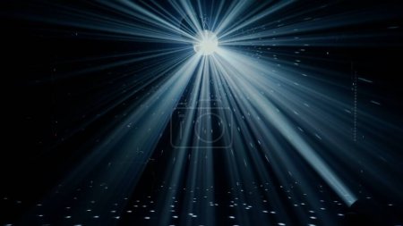 Photo for A disco ball hangs at the center of the image, casting bright rays of light across the dark expanse of a nightclub. The beams create a starburst effect, symbolizing the classic disco era and the - Royalty Free Image