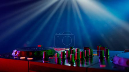 Téléchargez les photos : Cette image présente un gros plan d'un équipement professionnel de DJ éclairé par des néons. L'accent mis sur les platines tournantes et le plateau de mixage, avec des boutons et des curseurs aux couleurs vives - en image libre de droit