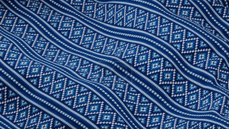 Téléchargez les photos : Textile bleu élégant avec motifs géométriques. L'image capture la beauté complexe d'un textile bleu orné de motifs géométriques. Le tissu est élégamment drapé, créant un flux harmonieux qui - en image libre de droit