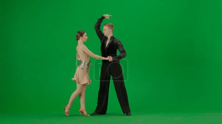 Photo for An elegant ballroom dance duo performs a dynamic routine captured against a vivid green screen background. This image is perfect for projects that require chroma key compositing, offering a versatile - Royalty Free Image