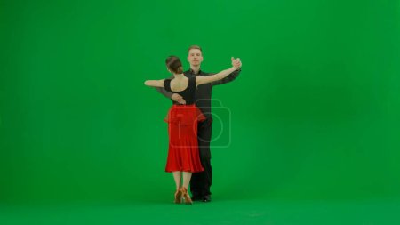 Téléchargez les photos : Un élégant duo de danse de salon exécute une routine dynamique capturée sur un fond vert vif. Cette image est parfaite pour les projets qui nécessitent une composition chromatique clé, offrant une polyvalence - en image libre de droit